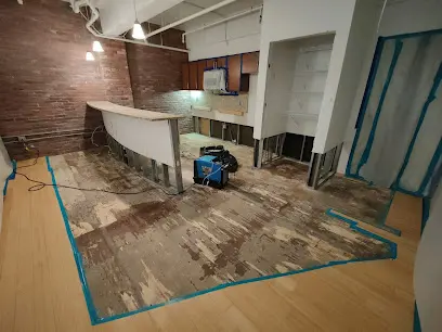 Kitchen floor cut out inside taped containment with an air mover drying the slab