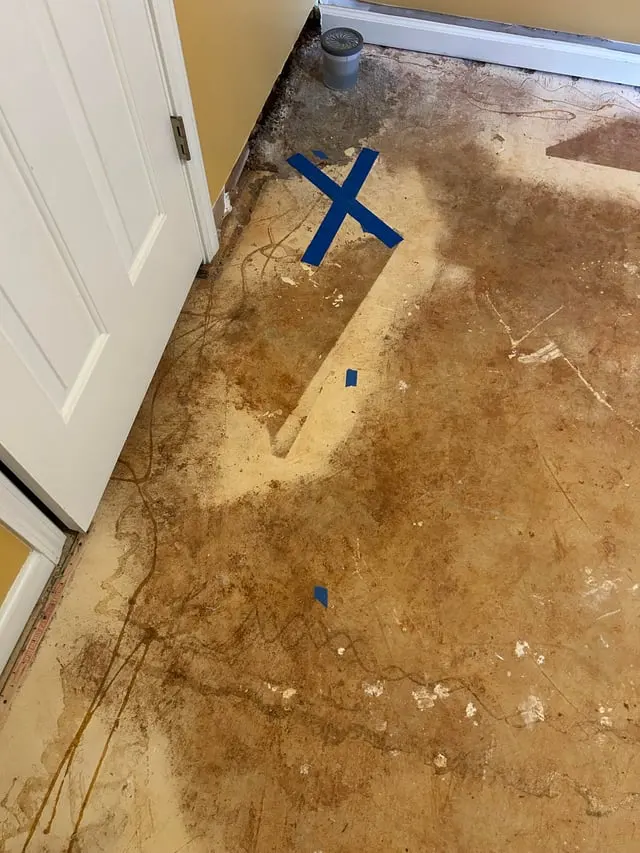 Concrete slab exposed after the flooring came up, with a water stain and a blue mark over the leak, slab leak water damage in Encinitas