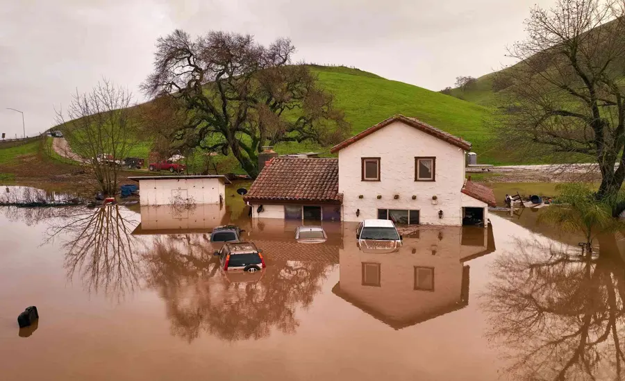 Floodwater surrounding a two-story house and parked cars after a heavy winter storm, storm and flood cleanup for Encinitas